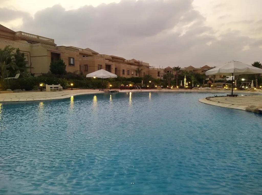 Una gran piscina de agua azul con edificios y sombrillas. en Cozy room, en El Cairo