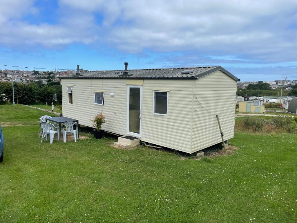 a small white house with a table in a yard at Kernow Wishes in Newquay