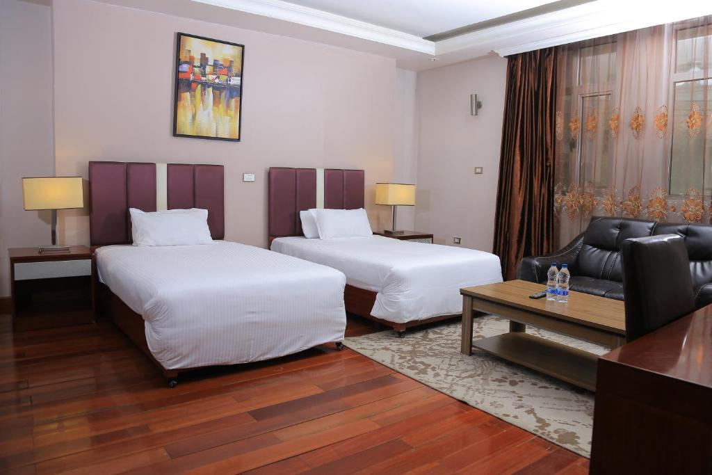 a hotel room with two beds and a couch at Yinm Luxury Apartment in Addis Ababa
