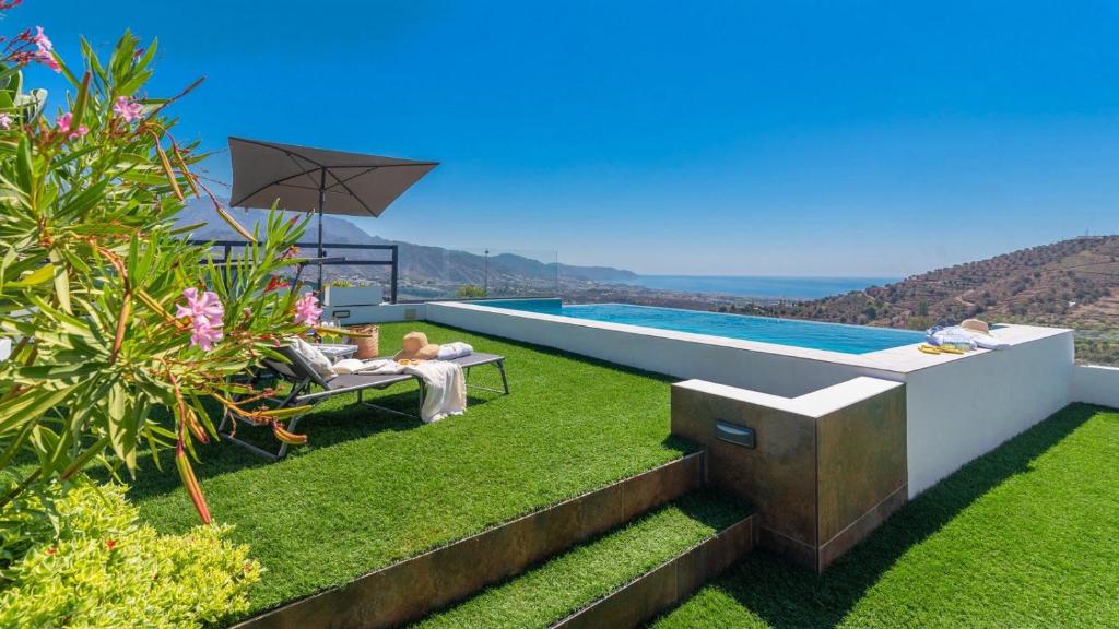 a person sitting on a chair next to a swimming pool at Villa Alborada Torrox by Ruralidays in Torrox