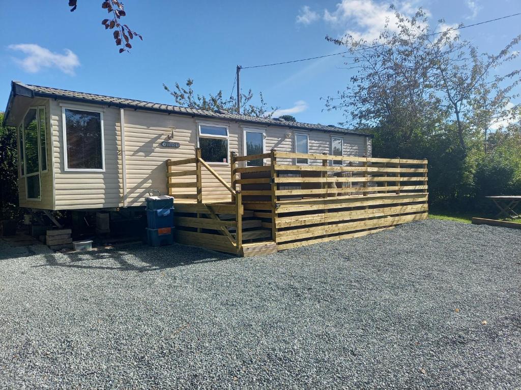 a yellow caravan parked next to a wooden fence at Emma 6 in Menai Bridge