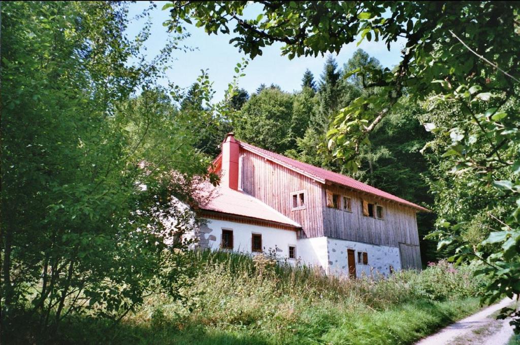 une ancienne grange rouge et blanche sur une colline avec des arbres dans l'établissement Grillnhäusl, à Wegscheid