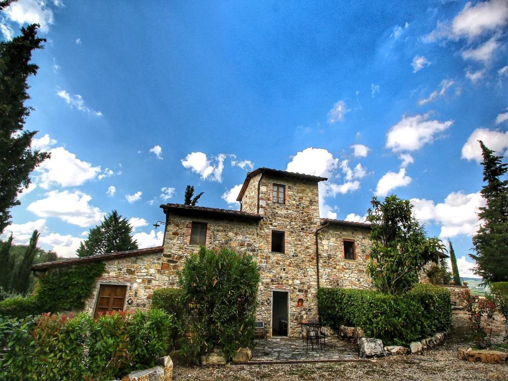 an old stone building with a blue sky and clouds at Pretty farmhouse with terrace in Radda in Chianti