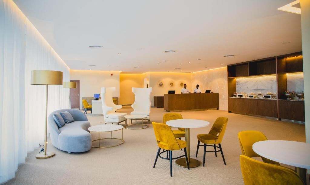 Contemporary hotel lobby lounge with curved seating, yellow chairs, and reception desk.