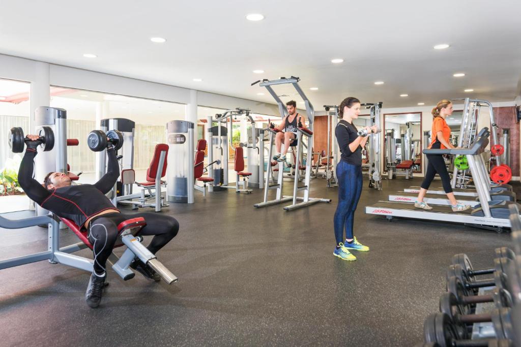 Fitness center with gym equipment, dumbbells, treadmills, and multiple exercising guests.