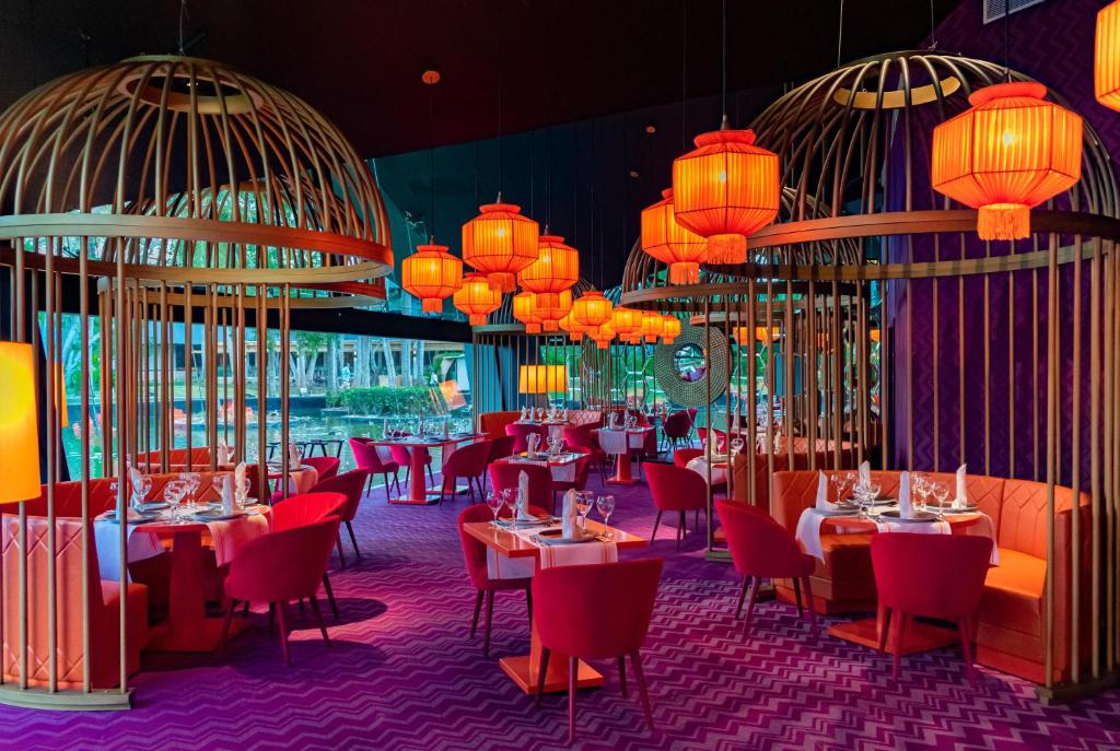Dining room with red chairs, gold cage fixtures, and orange pendant lights.