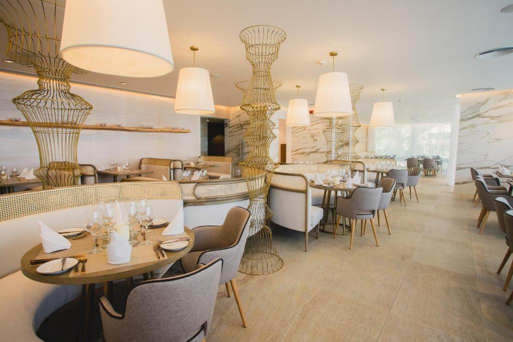 Modern restaurant dining room with round tables, brass pendant lights, and neutral decor.