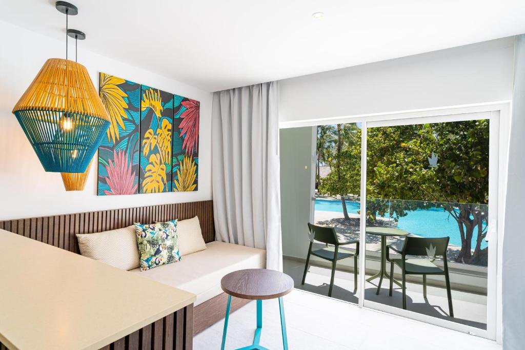 Room balcony view overlooking turquoise swimming pool and surrounding tropical vegetation.