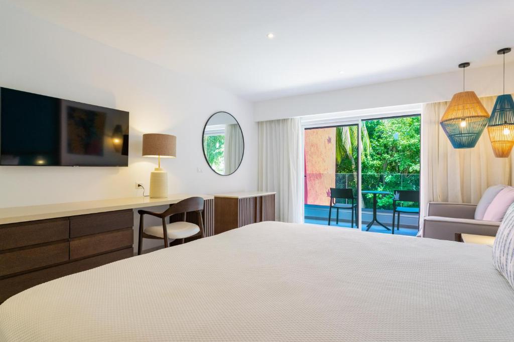 Bedroom with king bed, desk, wall-mounted TV, and sliding doors opening to pool view.