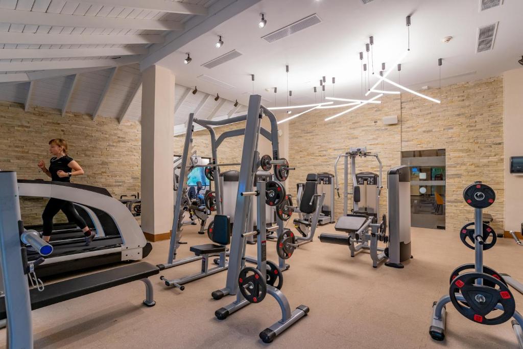 Fitness center with cardio equipment, weight machines, and free weights on beige flooring.