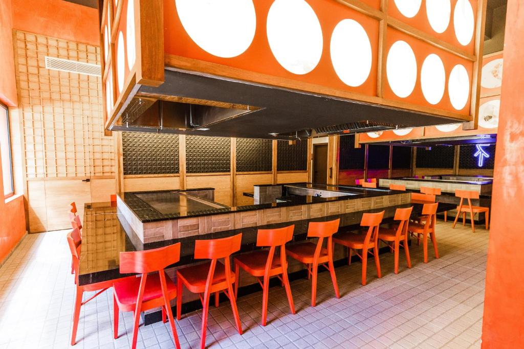 Modern bar with orange accents, black countertop, and orange seating for customers.