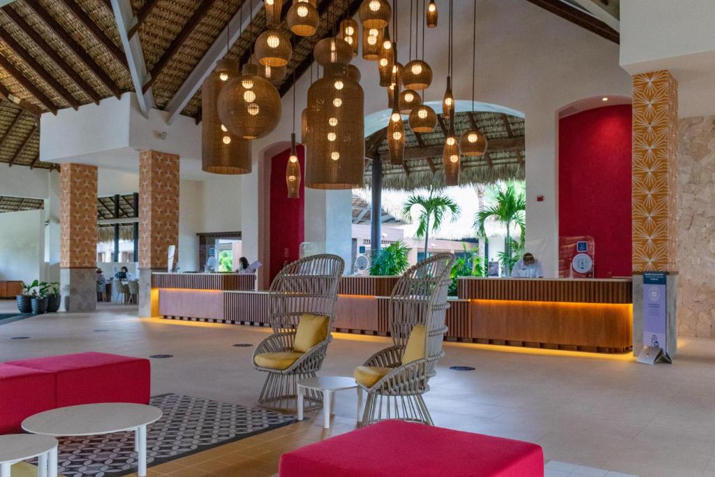 a lobby with chairs and tables and chandeliers at Tropical Deluxe Princess - All Inclusive in Punta Cana