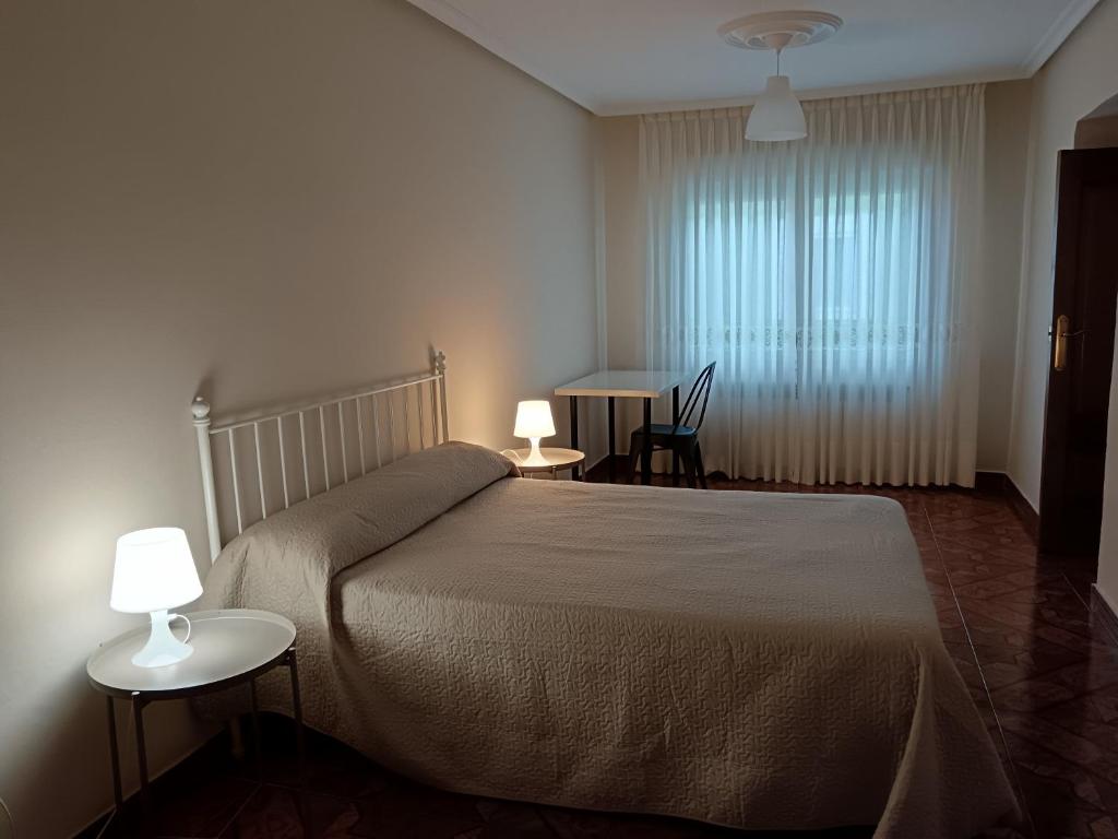 ein Schlafzimmer mit einem Bett, zwei Tischen und zwei Lampen in der Unterkunft Vivienda Vacacional Alba Marinas in Pravia