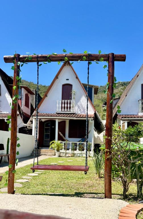 a swing in front of a house at Casa estilo chale dúplex com 3 quartos, churrasqueira, balanço, chuveirão e a uma quadra da praia in Mangaratiba