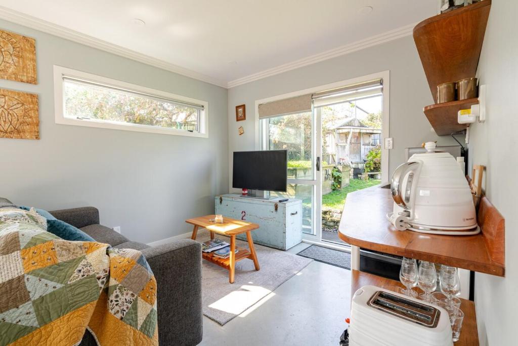 a living room with a couch and a tv at Modern Garden Cottage with Private Outdoor Area - New Lynn in Auckland