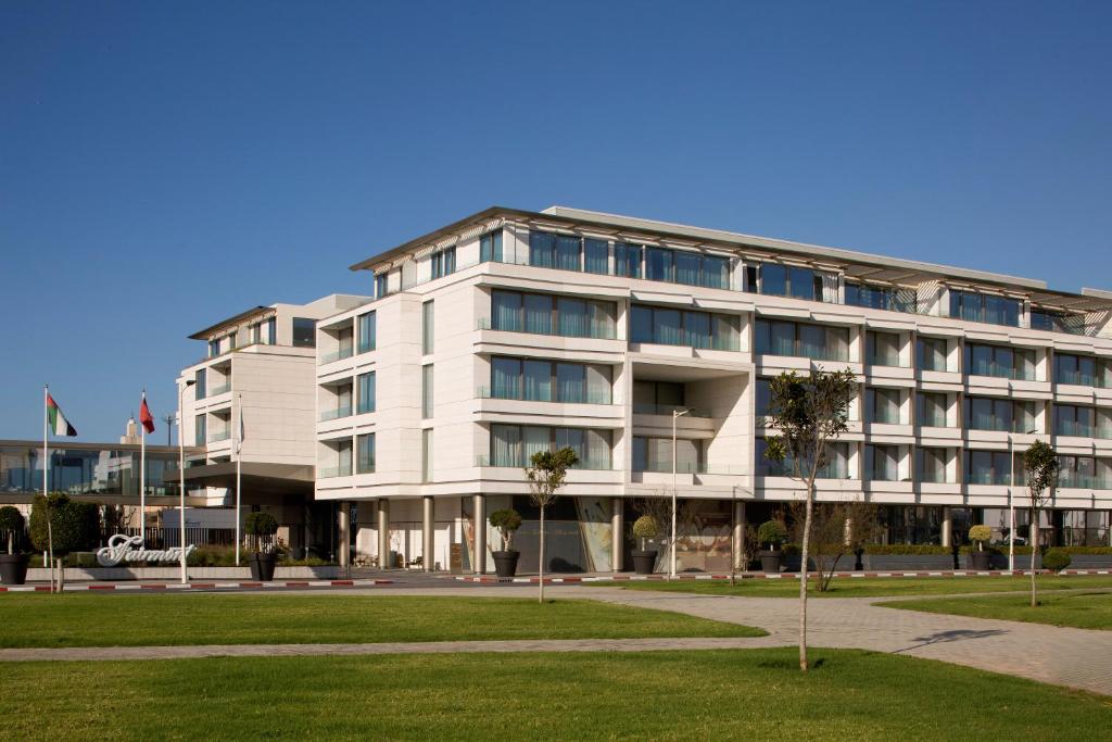 a large white building with palm trees in front of it at Fairmont Residences La Marina Rabat Sale in Rabat