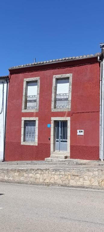 a red building with two windows on a street at El hogar de Gregorio in Vilvestre