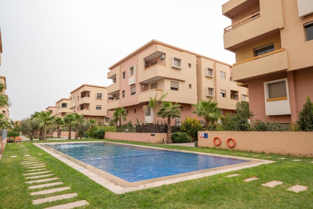 an apartment complex with a swimming pool in front of a building at Appartement Moyen Standing Piscine, Parking & Wifi in Marrakech
