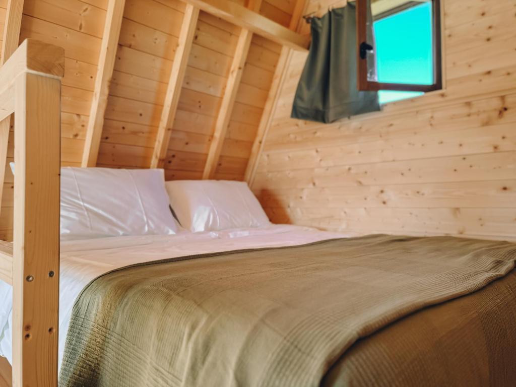 Ce lit se trouve dans une cabane en rondins dotée d'une fenêtre. dans l'établissement Fontaine aux Herbes - Ecolodge Humulus lupulus, à Clarbec