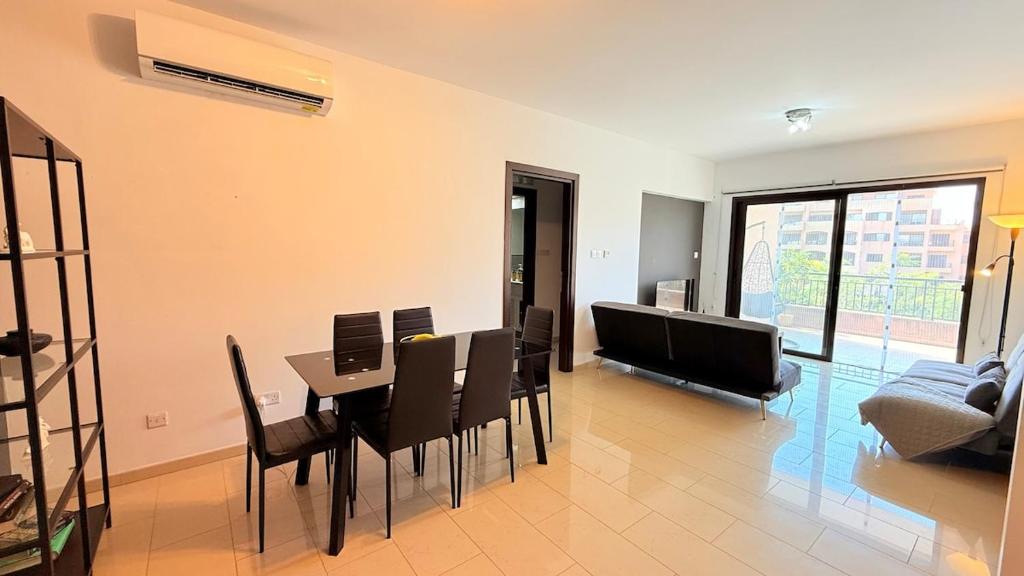 Una sala de estar con una mesa y sillas y un sofá. en Aphrodite Gardens Modern Apartment, en Paphos