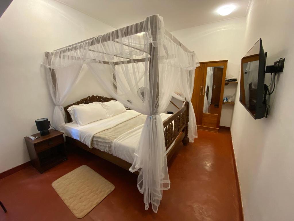 a bedroom with a canopy bed with white curtains at Dream Inn in Kandy