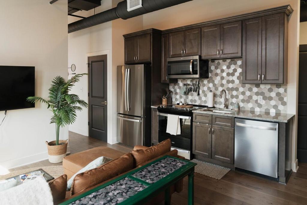 a kitchen with brown cabinets and a couch in a room at The Cozy Corner - Downtown Troy in Troy