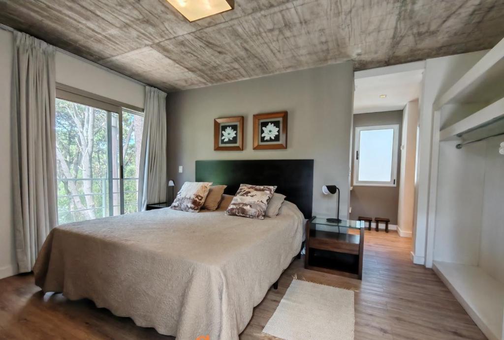 una camera da letto con un letto grande e una grande finestra di Casa en Barrio Cerrado en Rincón del Indio cerca del mar a Punta del Este