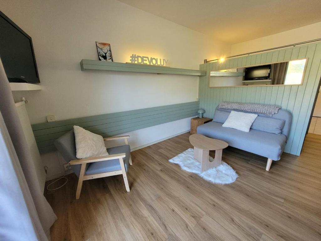 a small living room with a blue couch and a chair at appartement superdevoluy in Le Dévoluy