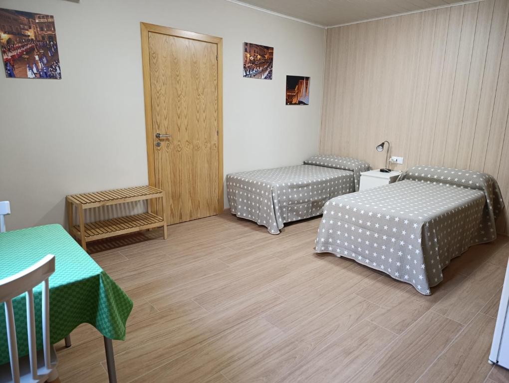 una camera con due letti e un tavolo e una porta di Habitación independiente II en Casa Rural Javier a Valmuel