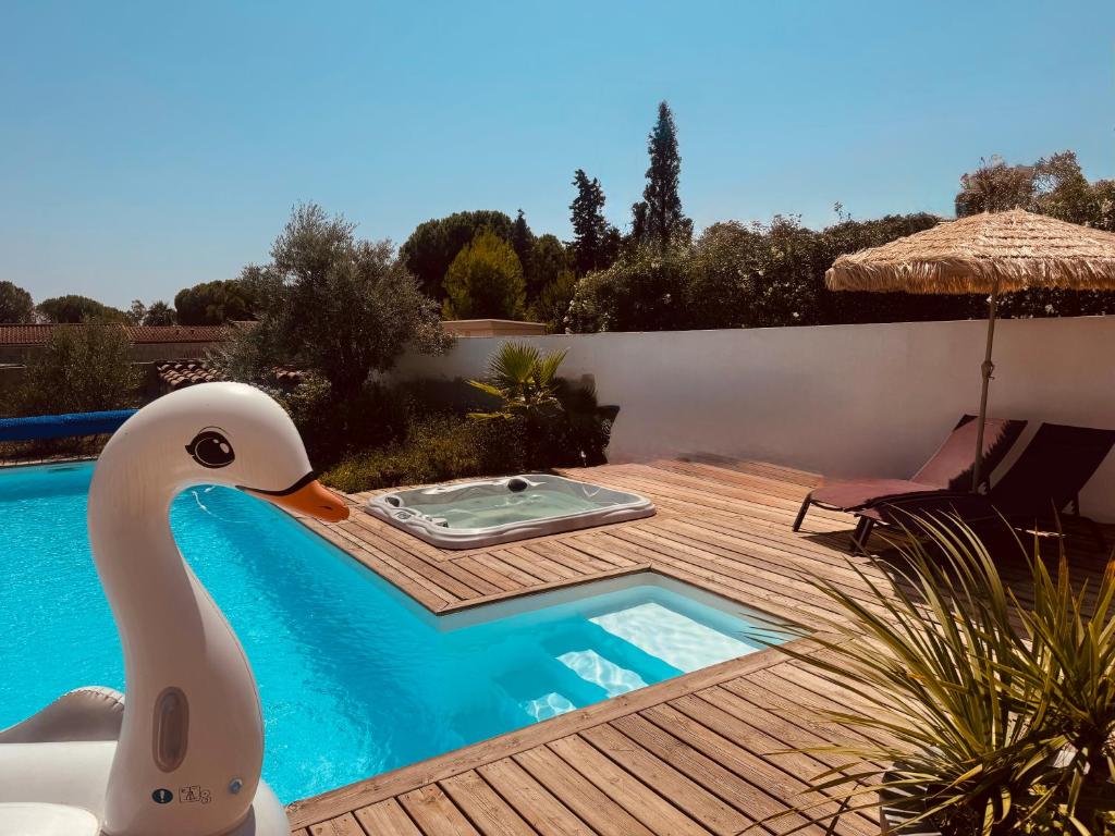 a duck sitting on a deck next to a swimming pool at Gîte Les Lauriers Roses in Marseillan