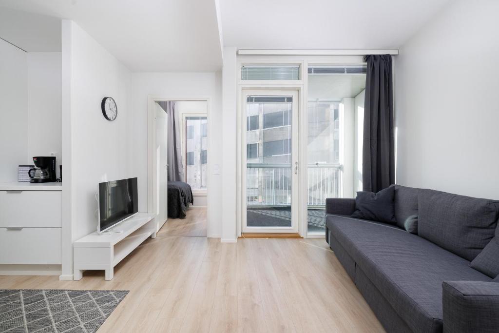 ULEABO New and bright downtown 3-room apartment في أولو: غرفة معيشة مع أريكة وتلفزيون