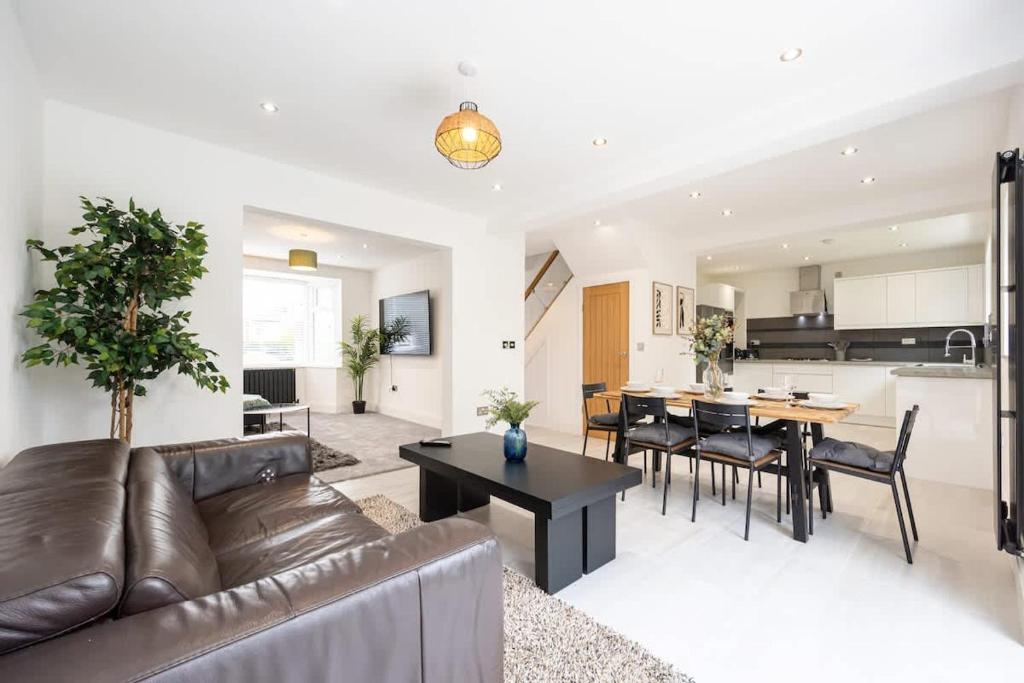 a living room with a couch and a table and a kitchen at The Wilmslow House Free Parking - Close to Airport in Alderley Edge