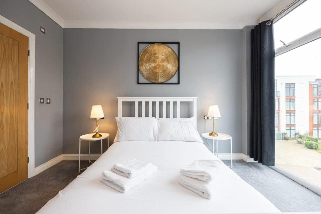a bedroom with a large white bed with two lamps at The Sharston - Free Parking & Close To Airport in Wythenshawe