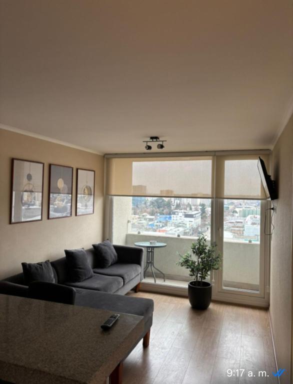 a living room with a couch and a large window at Moderno 1704 Depto en el Centro de Chillan con estacionamiento in Chillán