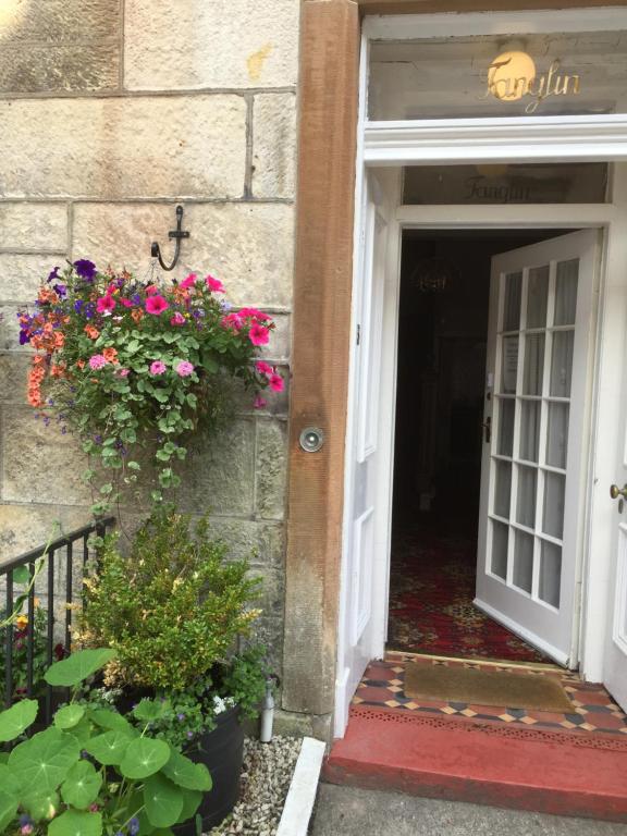 an open door with flowers on the side of a building at Tanglin Guest House in Oban