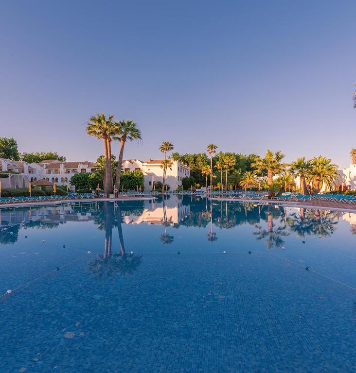 a large swimming pool with palm trees in the background at Resort house with Pools and Private beach in Tavira