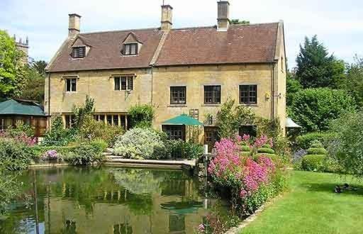 a large house with a pond in front of it at A Characterful Cotswolds Mill in Moreton in Marsh