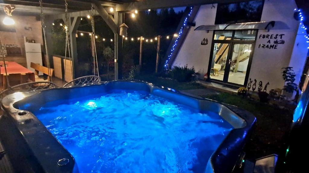a hot tub in the middle of a yard at night at Porumbacu Retreat-Cabana Forest A-frame și Chalet Max cu jacuzzi și piscină sezonieră, pe malul râului ,în apropiere de Transfăgărășan, Sibiu in Porumbacu de Sus