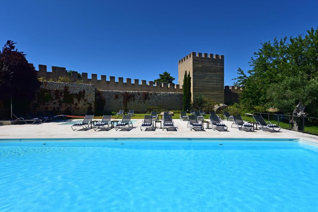 a swimming pool with chairs and a castle at Pousada Castelo de Alcacer do Sal in Alcácer do Sal