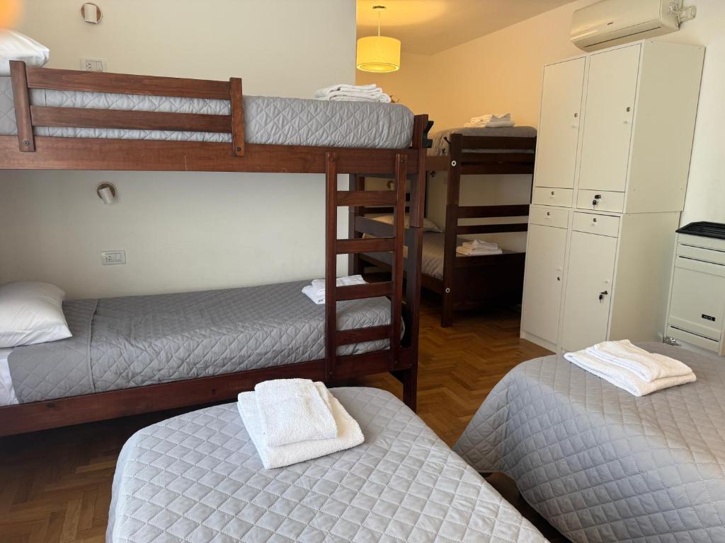 a room with three bunk beds and a room with twounks at La Via Hostel in Neuquén