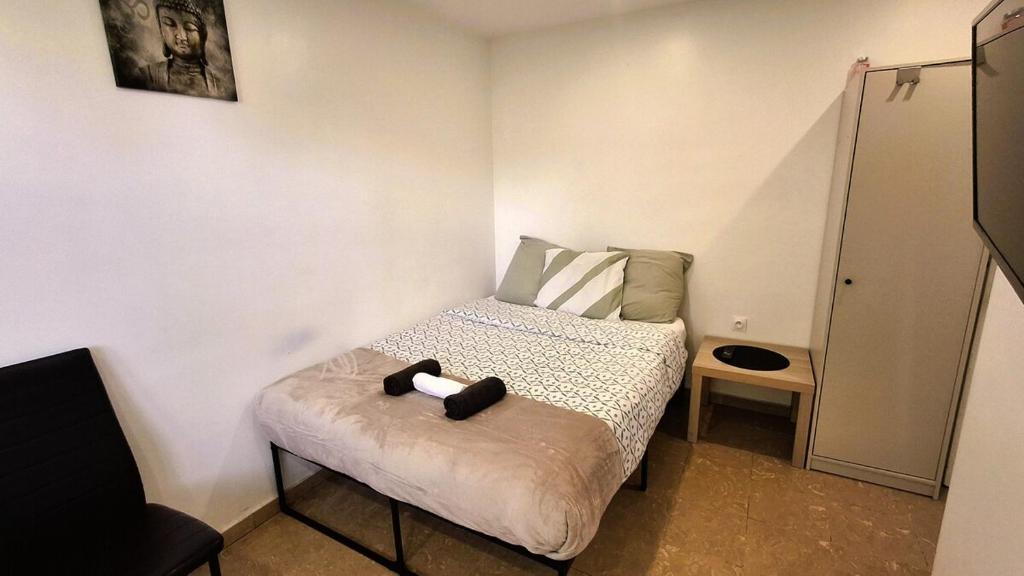 a small bedroom with a bed with a black object on it at Studio indépendant et bien équipé avec véranda commune in Neuilly-sur-Marne
