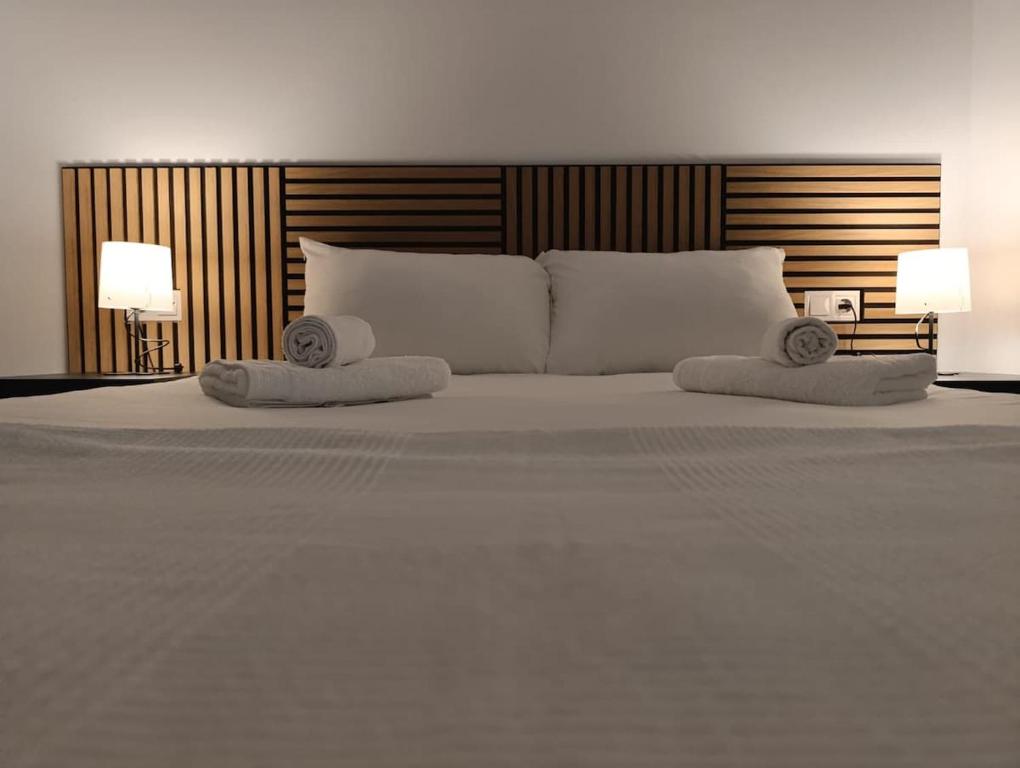 ein weißes Bett mit zwei Kissen und zwei Lampen in der Unterkunft Benalmádena Beach Apartment in Benalmádena