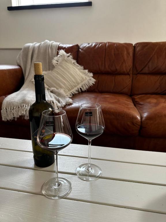 a bottle of wine and two wine glasses on a table at Wayeview Cottage on working Devon farm in Ipplepen