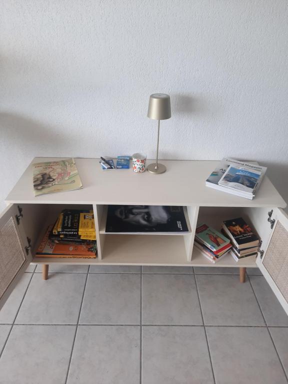 un escritorio blanco con una lámpara y libros. en Appartement vue mer - Calme - Parking - Tennis - Piscine été, en Sète