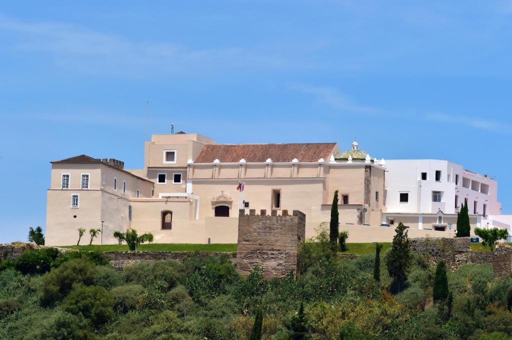 un grand bâtiment blanc au sommet d'une colline dans l'établissement Pousada Castelo de Alcacer do Sal, à Alcácer do Sal