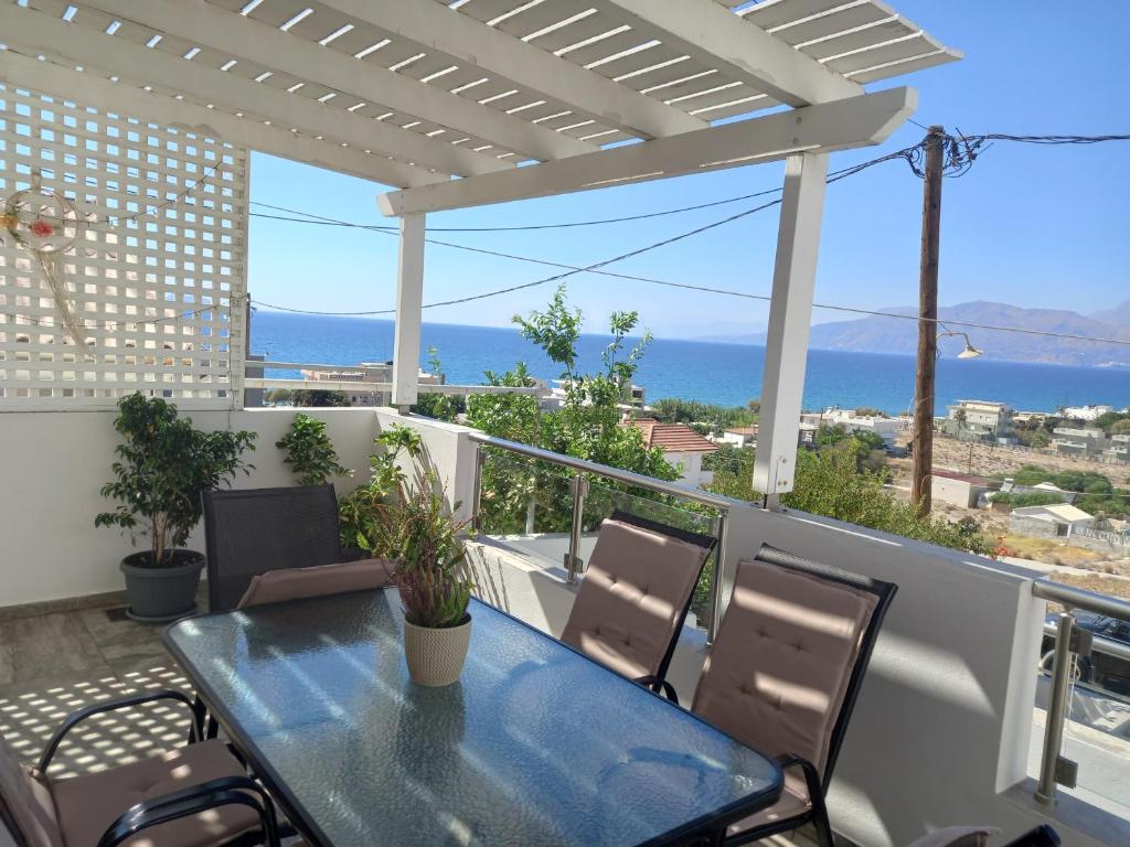 Una mesa y sillas en un balcón con vista al mar. en Elena House, en Kalamaki