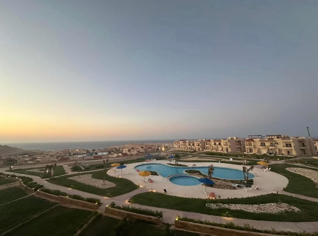 an aerial view of a resort with two pools at شاليه بقرية كورال هيلز الساحل الشمالي برأس الحكمة in Jalāl