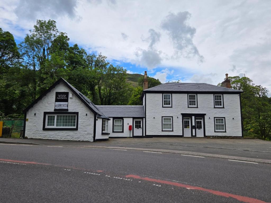 a white building on the side of a street at The Post Office Tarbet in Tarbet