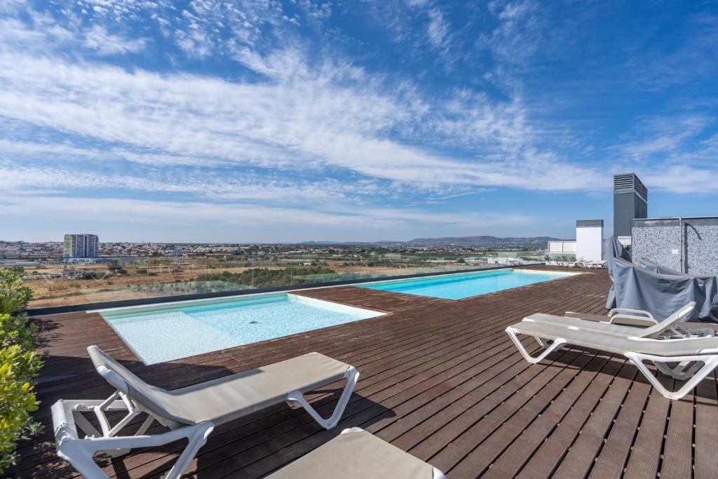 a deck with two chairs and a swimming pool at Rooftop Pools & Balcony Haven by HostWise in Faro