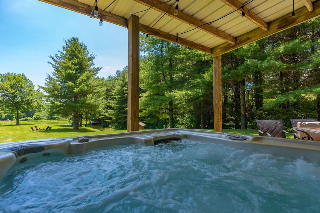 a hot tub in a backyard with a pergola at Secluded Getaway- 10 Mins to Blue Ridge Parkway, Sleeps 8, Hot Tub, Fire Pit in Ennice